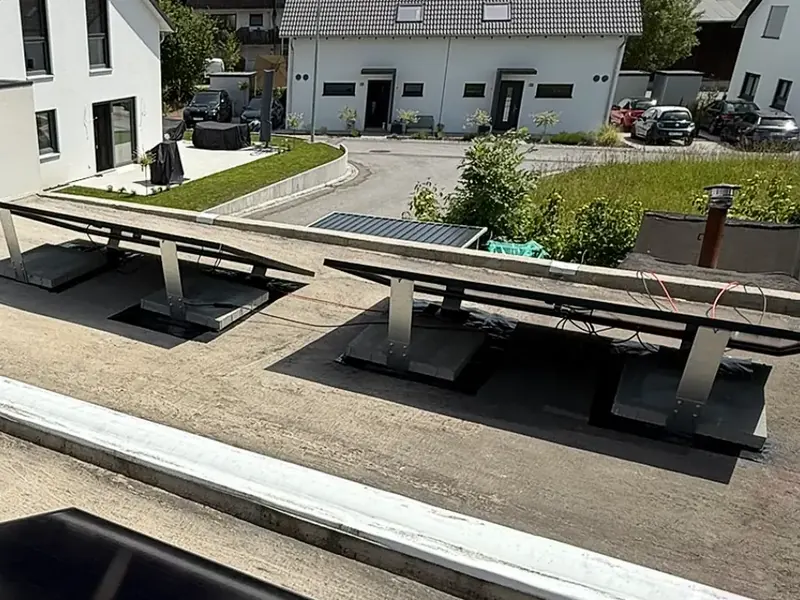 Aufgeständerte Solarmodule auf einem Flachdach, beschwert mit Betonplatten