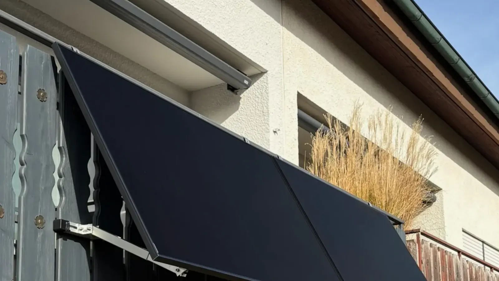 Zwei schwarze AIKO-Solarmodule schräg an einem Balkon