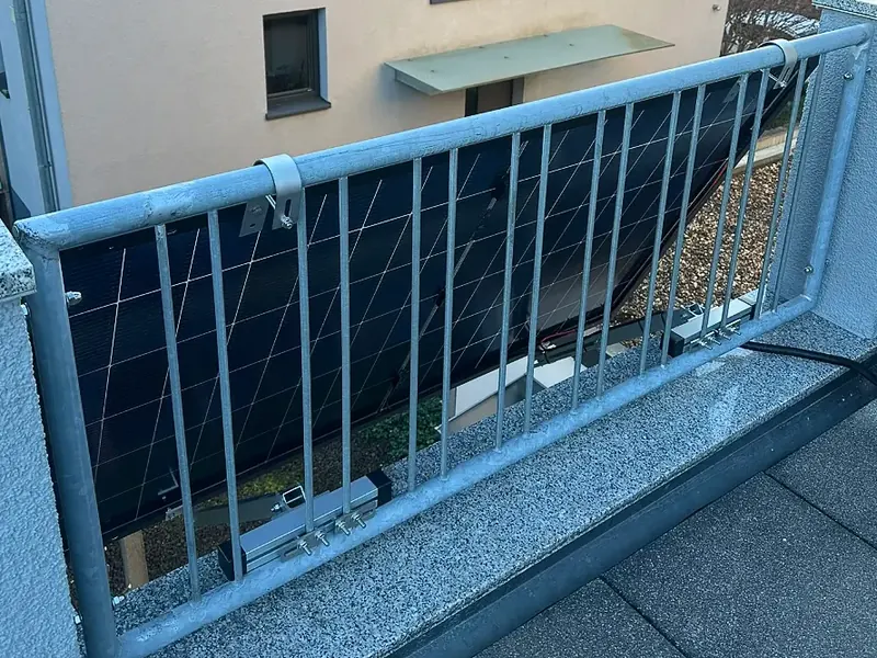 Solarmodul mit Halterung hinter einem Gittergeländer am Balkon