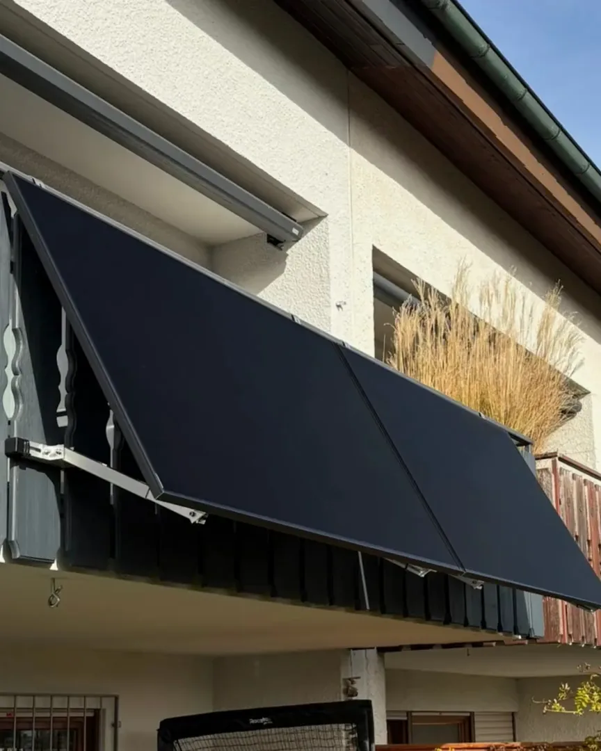 Zwei schwarze Solarmodule an einem Holzgeländer
